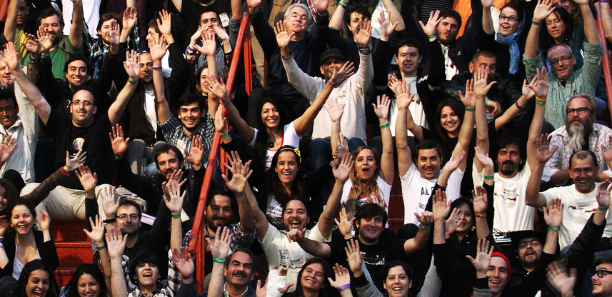 rows of dozens of people sitting on stairs, raising their arms in celebration of the Media Party in Buenos Aires